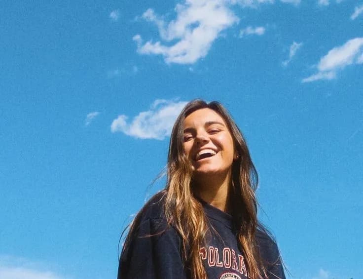 Person laughing against blue sky